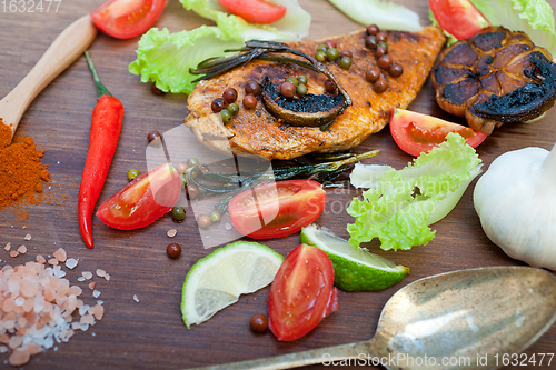 Image of wood fired hoven cooked chicken breast on wood board 