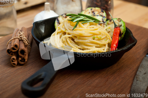 Image of italian spaghetti pasta with zucchini sauce on iron skillet