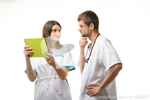 Image of Doctor looks thoughtfully at a nurse with a tablet computer in his hands