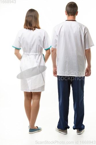 Image of A man and a woman in medical clothes stand with their backs, full height