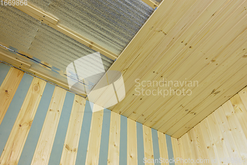 Image of finishing of the ceiling insulated with foamed polyethylene with wooden clapboard during the construction of a country house