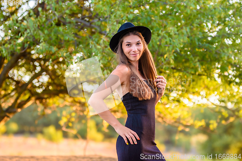 Image of Portrait of a beautiful girl on a background of blurry green foliage