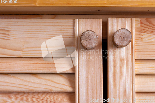 Image of wooden homemade handles on the wooden facades of the kitchen set