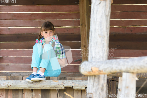 Image of A ten-year-old girl sits in a wooden gazebo and looks thoughtfully into the distance