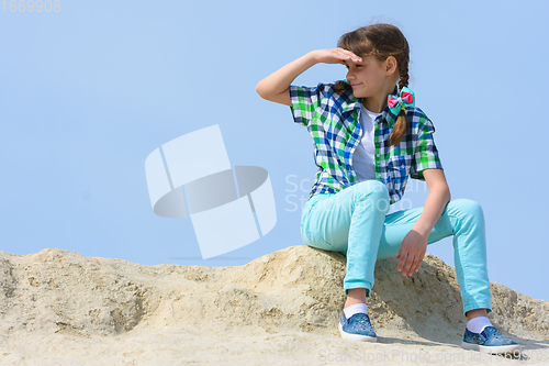Image of The girl sits on the top of the hill and looks into the distance