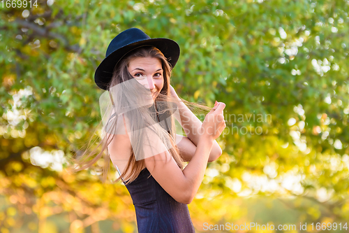 Image of Portrait of a beautiful girl against a background of blurry foliage, the girl temptingly covered her face with a lock of hair