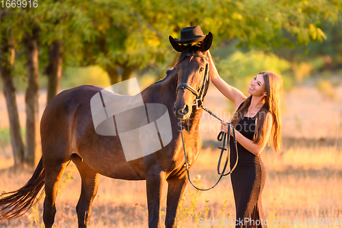 Image of The girl put on a hat on a horse for a walk and admires the horse