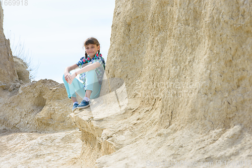 Image of Girl in casual clothes sits on a cliff ledge