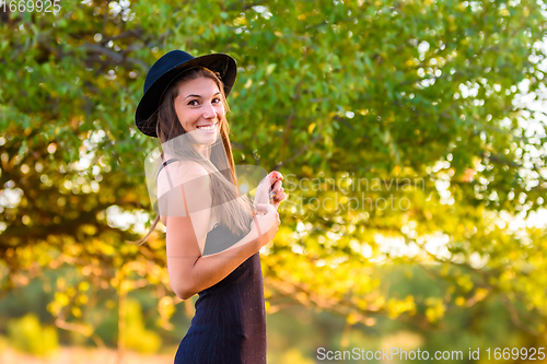 Image of Portrait of a beautiful girl, turned and looked into the frame, against a background of blurred foliage