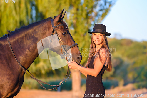 Image of The girl stands in front of the horse and turned and looked into the frame