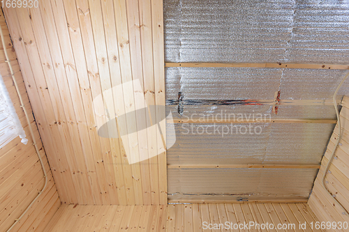 Image of Partially finished ceiling with clapboard in the room of a wooden house