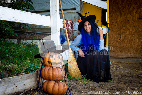 Image of Halloween celebration witch and pumpkin figure sit by the fence