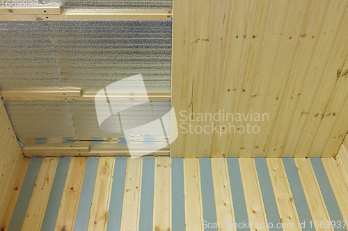 Image of finishing with wooden clapboard ceiling in the room of a country house