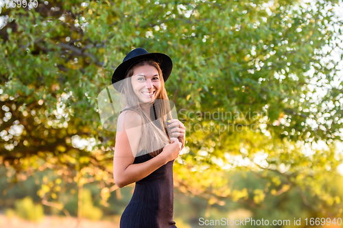 Image of Portrait of a beautiful cheerful smiling girl on a background of blurry foliage