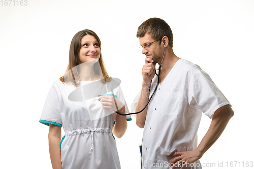 Image of The doctor listens with interest to the girl\'s heart with a phonendoscope
