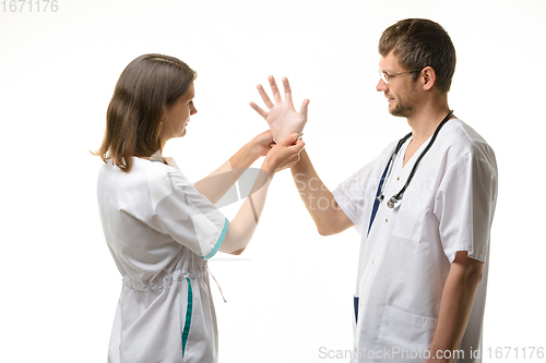 Image of A nurse helps a doctor put on rubber sterile gloves