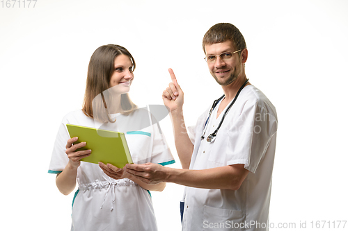 Image of Two doctors discuss the test results, one of them happily threw up a finger