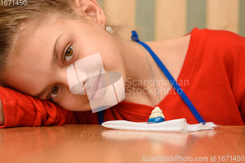 Image of The girl laid her head on her hand and looked into the frame, painting dough figurines at the table