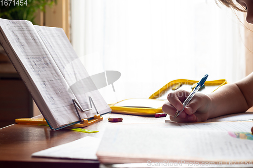 Image of Child\'s hand writes in a notebook while doing homework, close-up