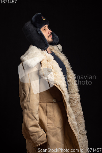 Image of Portrait of a Caucasian-looking man in a Soviet officer\'s fur hat and an army sheepskin coat, standing at attention