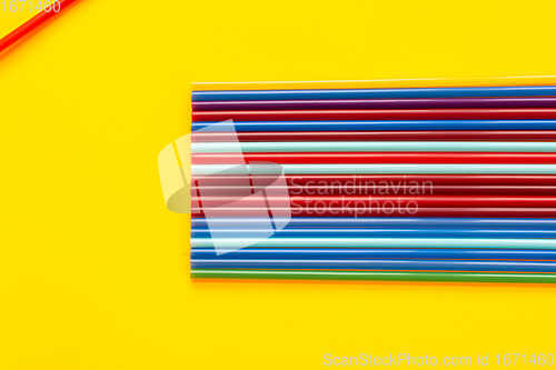 Image of On a yellow background, there are a dozen multi-colored cocktail tubes, in the corner there is another tube