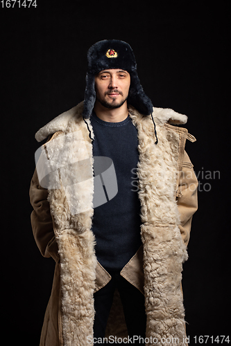 Image of Portrait of a confident man of Caucasian appearance in a Soviet officer fur hat and army sheepskin coat