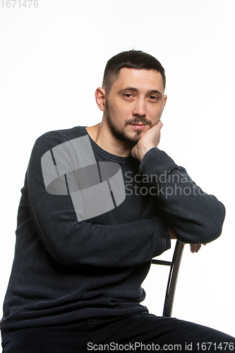 Image of Portrait of an ordinary man in a dark plain sweater sitting on a high-backed chair