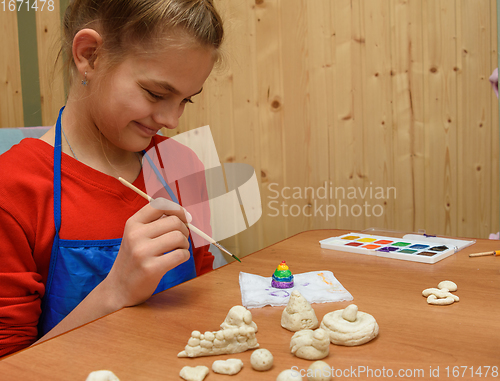 Image of Girl rejoices at the finished painted figurine made of salt dough