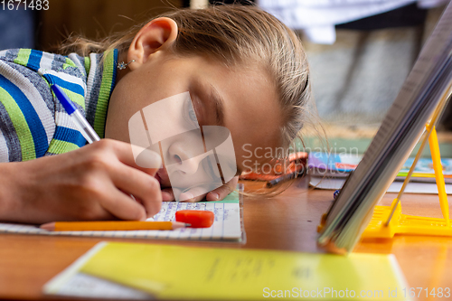 Image of Girl from fatigue put her head on the table doing homework