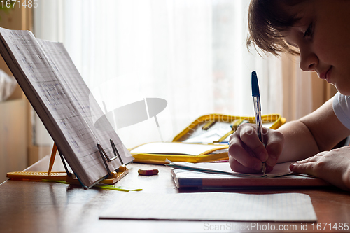 Image of Girl doing homework sitting at the table by the window