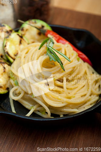 Image of italian spaghetti pasta with zucchini sauce on iron skillet