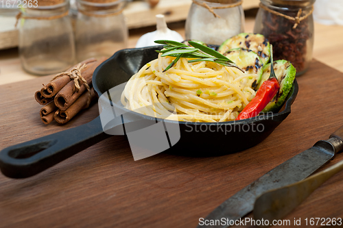 Image of italian spaghetti pasta with zucchini sauce on iron skillet