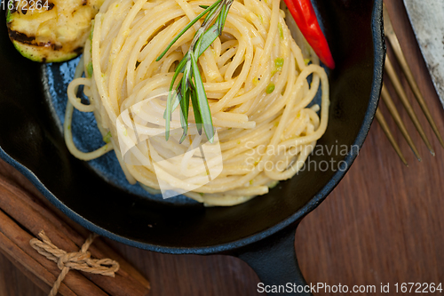 Image of italian spaghetti pasta with zucchini sauce on iron skillet