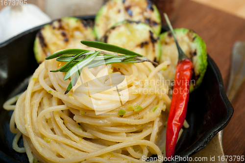 Image of italian spaghetti pasta with zucchini sauce on iron skillet