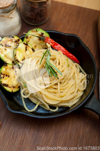 Image of italian spaghetti pasta with zucchini sauce on iron skillet