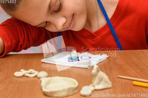 Image of A girl admires a beautifully painted dough figurine