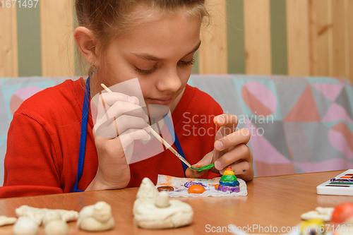 Image of A girl at home paints a craft made from salt dough