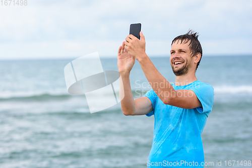 Image of A man communicates via video communication using a mobile phone while relaxing on the sea