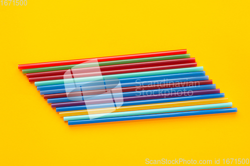 Image of A dozen multi-colored cocktail tubes lie on a yellow background