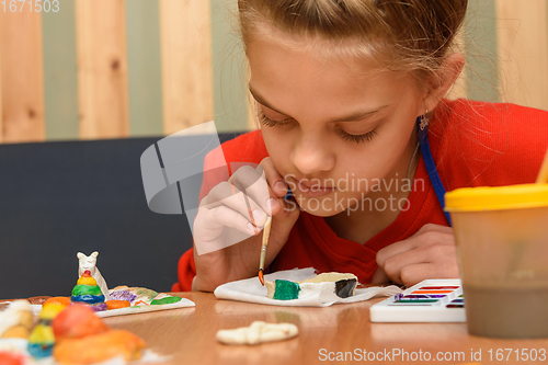 Image of A girl enthusiastically paints a puff pastry craft with watercolors