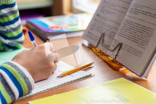 Image of Close-up view of the hands of a schoolboy doing homework