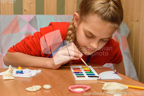 Image of A girl chooses a color of watercolors for coloring dough figurines