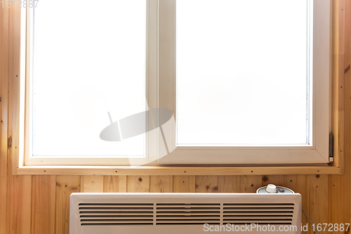 Image of Plastic window installed in a country house, under the window there is an electric heating radiator