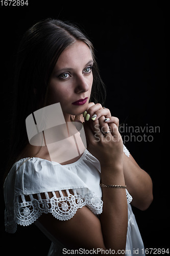 Image of Portrait of a beautiful girl thoughtfully putting her hands to her chin