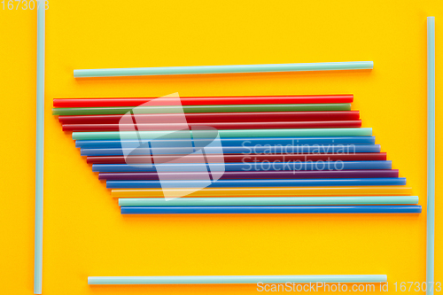 Image of A bunch of multicolored cocktail tubes lies on a yellow background