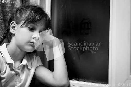 Image of Girl draws figures of little men on a fogged window