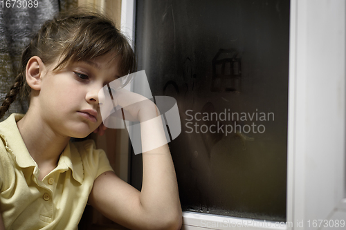 Image of A frustrated girl sits at a foggy window and is sad