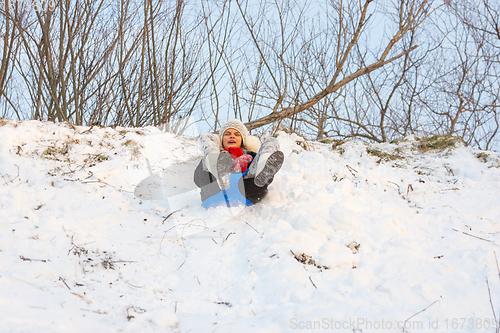 Image of A girl is rolling down a snow-covered slide while sitting on a plastic ice floe