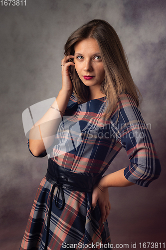 Image of Portrait of a beautiful girl in an interesting checkered dress on a gray background