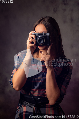 Image of Girl photographer takes pictures with an old camera, studio photography on a gray background